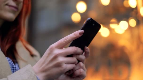 Mujer usando la aplicación en el teléfono móvil durante el paseo por las calles de la ciudad vieja. Primer plano, estilo de vida, urbano, bokeh. Mensajes de texto femeninos con teléfono móvil, escribiendo mensajes de texto en el teléfono celular al aire libre — Vídeos de Stock