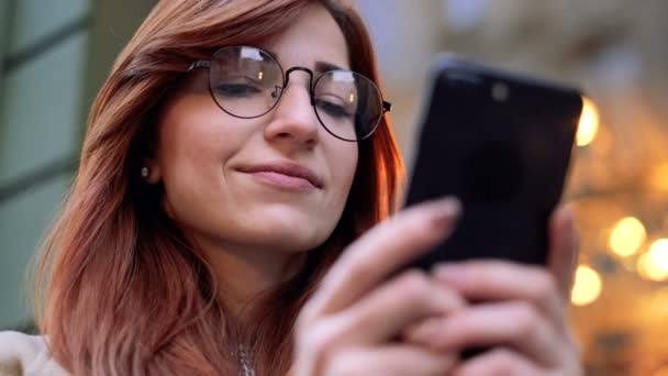 매력적인 젊은 사업가 hipster 학생 여자 인터넷 검색의 도시 도시 거리, 근접 촬영에서 스마트폰 애플 리 케이 션을 사용 하 여. 여자는 스마트 휴대 전화를 사용 하는 소셜 미디어 사이트를 스크롤. — 비디오