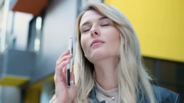 Uzun saçlı görüşmeleri o cadde boyunca yürür iken telefon ile sarışın kız. Portre, yaşam tarzı, kentsel kapatın