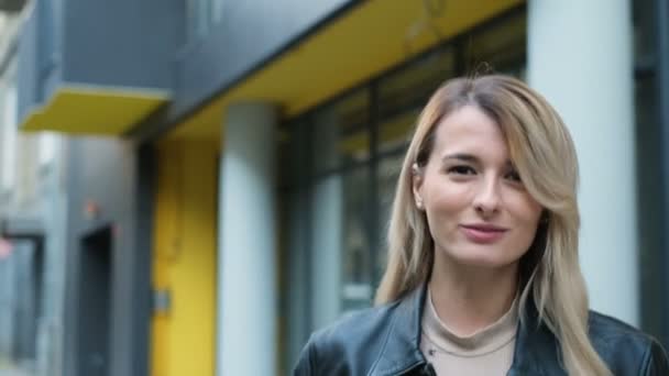 Retrair de menina hipster sorridente atraente caminhar pela rua, vira-se para a câmera e sorri. Retrato ao ar livre de jovem bela menina adolescente caucasiana sorrindo e olhando para a câmera — Vídeo de Stock