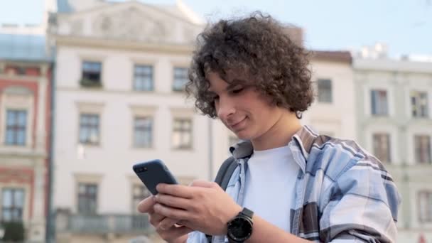 Primer plano retrato del hombre mensajes de texto utilizando la aplicación en el teléfono inteligente en la ciudad. Turista o estudiante, chats o mensajes de texto en smartphone, se mantiene en contacto con amigos o familiares — Vídeos de Stock