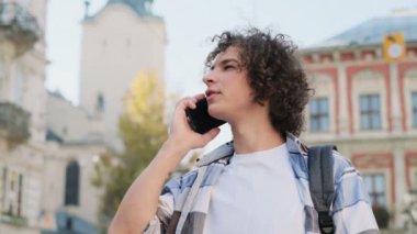 Smartphone üzerinde konuşan genç adam. Mutlu genç casual adam cep telefonuyla dışında şehir merkezinde. Evet ve gülümseyen yakışıklı bir hipster portresi.