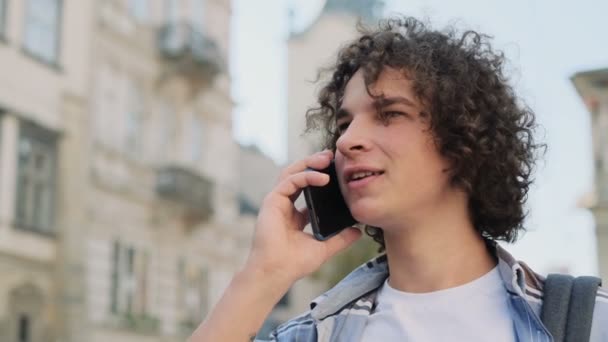 Close-up portret młody człowiek mówi na smartfonie. Szczęśliwy młody facet na co dzień, za pomocą telefonu komórkowego, poza, w centrum miasta. Portret przystojny rozmawia przez telefon i uśmiechając się. — Wideo stockowe