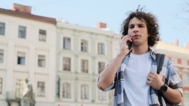 Bir adam telefonda konuşurken ve gülümseyerek. Yakışıklı blogger, açık havada yürüyüş ve hareket eden smartphone üzerinde konuşurken öğrenci portresi. Eğitim, seyahat, turizm kavramı