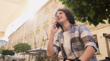 Bir adam telefonda konuşurken ve gülümseyerek. Yakışıklı blogger, açık havada konuşmak smartphone öğrenci portresi. Eğitim, seyahat ve Turizm kavramı