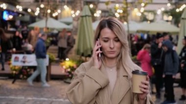 Şık genç Sevimli gülümseyen kız şehirde yürürken modern akıllı telefon kullanarak portresi. Dışarı gitmek smartphone üzerinde konuşmak ve kahve içme Bayan
