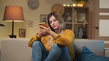 Cep telefonu, manifatura mesaj ile kanepede oturan yorgun kız. El, uykulu öğrenci cihaz ile çok fazla zaman harcama yorgun ağzıyla sıkılmış kadın evde Smartphone esneme kapsayan