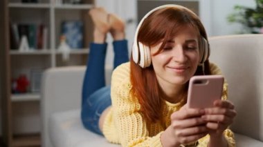 Bir kanepe oturma müzik ve cep telefonu evde tarama odasında yatan Kulaklığımda sevimli kız portresi. Rahatlatıcı ve düşünceli bir görünüm. Güzel ev atmosfer