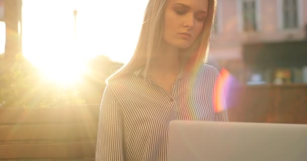 Un retrato de cerca de una mujer que trabaja en su computadora portátil mientras la cámara se mueve hacia arriba y captura rayos de sol . — Vídeos de Stock