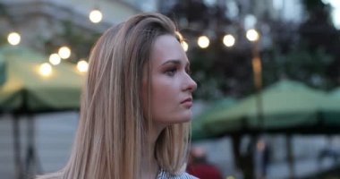 Bir kenara görünümlü ve yüzünü kameraya dönüm ve içtenlikle gülümseyen oldukça romantik bir kız portresi. Gece şehir ışıkları arka planda. Yakın çekim portre