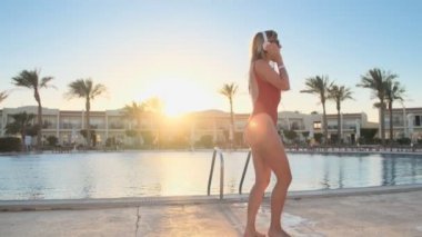 Güzel kadın kırmızı mayo ve kulaklık havuzu Beach eğlenceli dans ve smartphone uygulama Bikini kız yaz tatil keyfi yerinde güneş gözlüğü kullanarak müzik dinleme.
