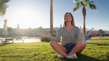 Genç Kafkas kadın tarafından pratik yoga açık mavi Havuzu, gyan mudra ve lotus pozisyonu yakın yeşil çimenlerin üzerinde rahatlatıcı. Sunrise arka plan. Kız rahatlatıcı Resort tatil, meditasyon egzersiz sırasında