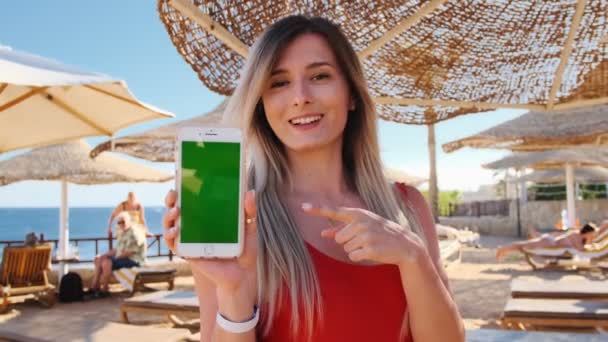 Dívka na dovolené ukazují zelená obrazovka smartphone venkovní. Zblízka žena ruku držení a používání mobilního telefonu s vertikální chroma klíč. Sexy žena v červené tělo pomocí mobilního telefonu v luxusní hotel. — Stock video