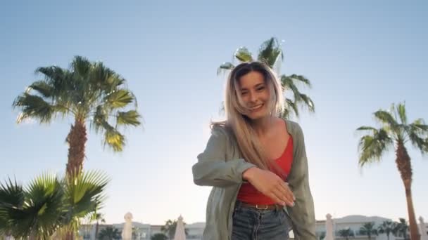 Follow me, young laughing running girl asking you to follow her, waving hand. Woman in red body swimsuit jumping, on hot sunny day. Summer holiday at luxury hotel, background swimming pool and palmas. — Stock Video