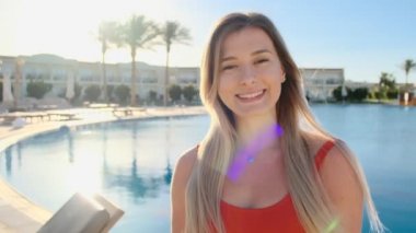 Genç kız, kameraya gülümseyen yüz portresi kapatın. Sıcak güneşli mavi Yüzme Havuz kenarında kırmızı mayo güzel kadın. İyi vakit geçiriyor kız yaz tatili lüks Villa.