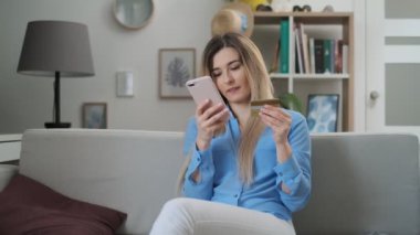 Mutlu ve gülümseyen bir kadın faturaları ödemek için akıllı telefon üzerinden bir kart ödeme yapıyor. Çekici bir kız işlem yapmak için cep telefonu banka veya kredi kartı bilgilerini koyarak. Alışveriş, bankacılık online.