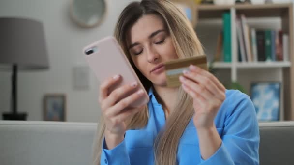 Kredi kartı tutan ve akıllı telefon kullanan genç bir kadın. Çevrimiçi alışveriş kavramı, dijital mobil aygıt kullanarak kolay ödeme. — Stok video