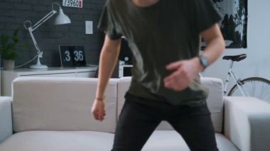 Yakışıklı bir genç odasında kanepede oturur ve kameraya bakar.