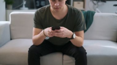 Kanepede oturan bir uygulama kullanarak bir çocuğun ön görünümü, kameraya bakar