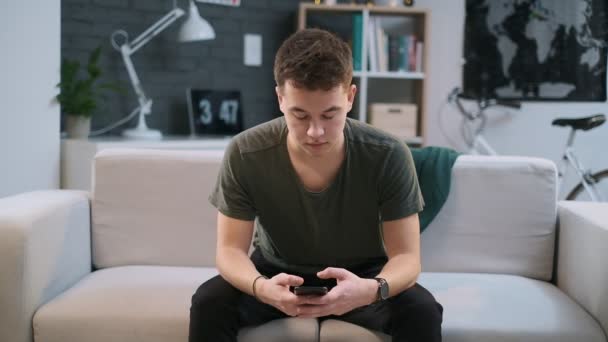 Een jongen gebruikt een app op zijn telefoon en verandert het scherm vervolgens in de camera en wijst er met zijn vinger op — Stockvideo