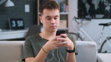 Bir çocuk bir uygulama kullanarak mutlu ve bir kanepede onun kulaklık müzik dinlerken, portre