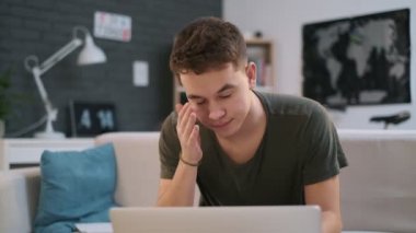 Kanepede dizüstü bilgisayarında çalışan bir çocuk sinirleniyor çünkü bir şeyler ters gidiyor.