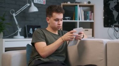 Kanepede oturan ve tabletinde web sufring genç bir adamın portre görünümü