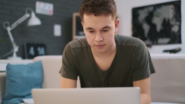Een jonge jongen werkt aan zijn laptop wanneer hij plotseling verward en teleurgesteld wordt — Stockvideo