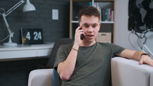 Close-up portrait of a sweet stylish teenage boy talking on the phone at home — Stock Video