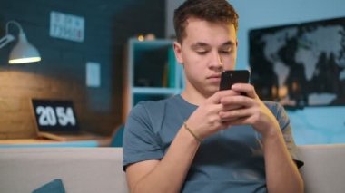 Sevimli bir çocuk ışıkları açık akşam evde akıllı telefon yazıyor