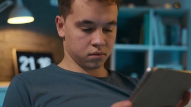 Odasında bir kanepede otururken dikkatle tabletine bakan bir çocuğun yakından görünümü