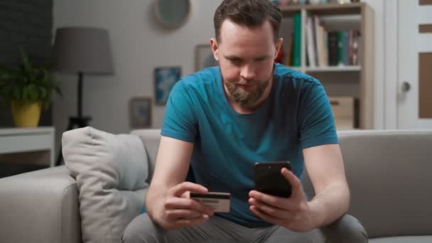 Homem comprando on-line, usando smartphone e um cartão de crédito em casa, aplicativo de celular de compras. Homem feliz segurando cartão de crédito, pagamento fácil usando o aplicativo de dispositivo móvel digital tecnologia de internet de negócios inteligente . — Vídeo de Stock