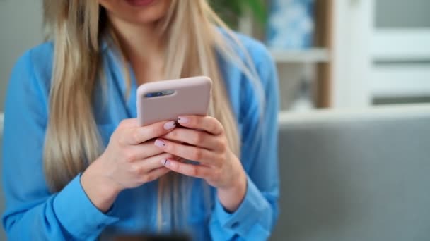 Nahaufnahme von Frauenhänden, die ein rosafarbenes Handy in der Hand halten, Mädchen, die per App SMS schreiben und Videos auf dem Mobiltelefon ansehen, genießen das Lesen sozialer Medien zu Hause. — Stockvideo