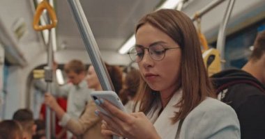 Toplu taşıma. Toplu taşımacılıktaki çekici genç kız akıllı telefon konuşmaları ve arkadaşlarıyla mesajlaşmaları kullanıyor. Tramvayda seyahat ederken tırabzanı tutan tatlı bir kadın. Şehir, şehir, ulaşım.