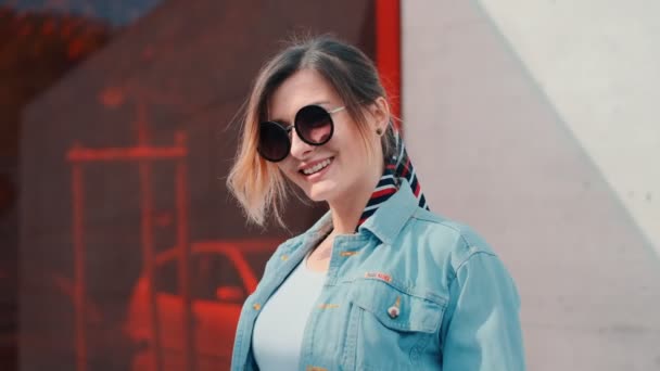 Porträtt av den kaukasiska snygga unga attraktiva kvinnan i solglasögon leende och poserar på kameran på den soliga dagen utomhus. — Stockvideo