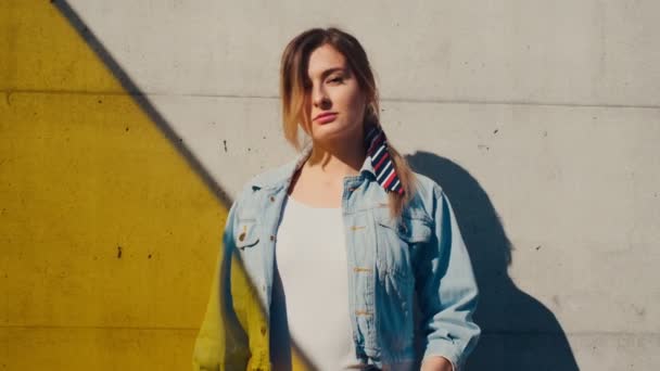 Caméra zoomant sur le visage de la jeune femme attrayante caucasienne modèle debout au mur en plein air et regardant dans la caméra. Effet lumière jaune. Portrait tourné . — Video