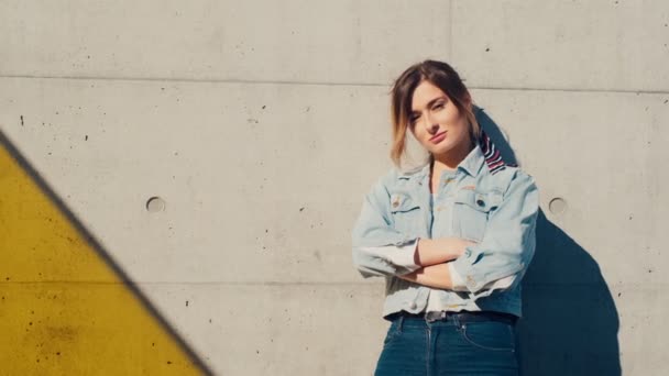 Portrait de la jeune fille élégante et jolie caucasienne debout au mur et penchée dessus avec les mains croisées devant elle. Extérieur . — Video