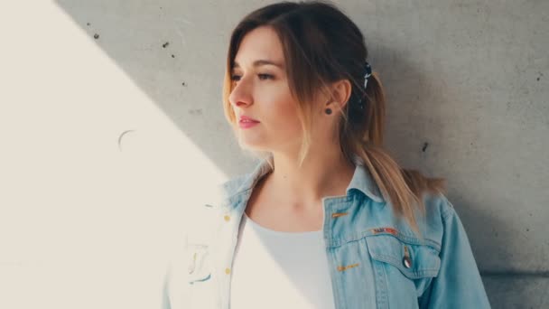 Cámara zoom en la cara de la chica caucásica bastante joven mirando a un lado, luego girando la cara a la cámara y sonriendo. Afuera. De cerca. Retrato . — Vídeo de stock