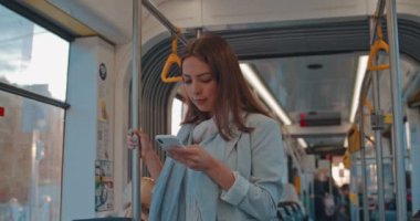 Sevimli kız Portresi, cep telefonu mesajlaşma ve toplu taşıma cep telefonu tarama, korkuluk tutar. Akıllı telefonu kullanan gülümseyen kadın. Şehir, kentsel arka plan