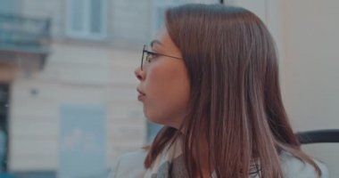 Toplu taşıma sırasında kameraya bakan gözlük takan genç çekici gülümseyen kız yüz portresi. Şehir, kentsel arka plan. Onu hedefe götürmek için otobüs bekleyen kadın.