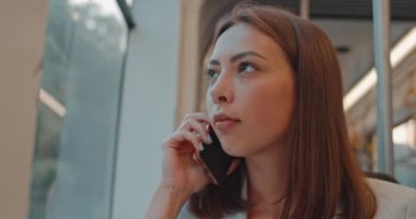 Kız toplu taşıma da cep telefonuyla konuşuyor. Onu günlük gidip sırasında şehir tramvay pencereyakınında oturma mutlu çekici kadın Yüz portre ve akıllı telefon konuşurken.