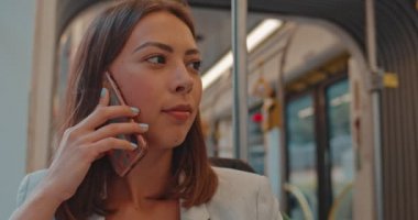 Kız toplu taşıma da cep telefonuyla konuşuyor. Mutlu çekici kadın akıllı telefon konuşuyor ve kamera ve gülümseme bakıyor.