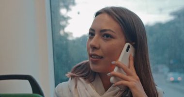 Kız akşam toplu taşıma cep telefonu yla konuşuyor. Onu günlük gidip sırasında şehir tramvay pencereyakınında oturma mutlu çekici kadın Yüz portre ve akıllı telefon konuşurken.