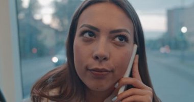 Yakın yüz portre kız toplu taşıma cep telefonu konuşuyor. Mutlu çekici kadın şehir tramvay pencereyakınında oturma, akıllı telefon konuşurken ve kamera bakarak.