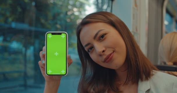 Mujer mostrando smartphone con pantalla verde vertical en transporte público. Mujer sosteniendo el teléfono celular con croma key y mostrando los pulgares hacia arriba gesto durante el viaje . — Vídeos de Stock