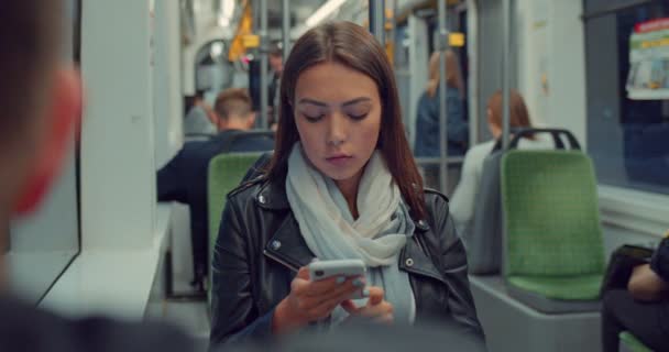 Muchacha sonriente atractiva en el transporte público utilizando el teléfono inteligente navegar por Internet y charlar con amigos. Ciudad urbana nocturna . — Vídeo de stock