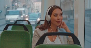 Beyaz kulaklıklı genç, güzel beyaz bir kadın boş bir tramvayda oturuyor ve eve giderken ya da işe giderken müzik dinliyor..
