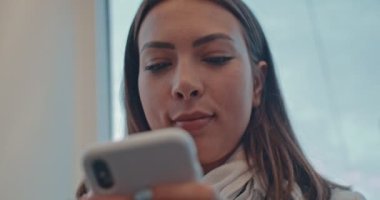 Aşağıdan, beyaz tenli genç kızın elindeki akıllı telefon cihazından bir mesaj gönderip dinlerken görüntüyü al. Kapat..