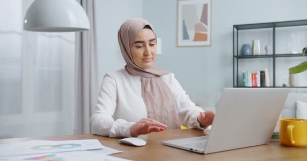 Beautiful asian muslim student girl start working on laptop, opening computer, study online with internet teacher, thinking solving problem at home. Serious woman search for inspiration and ideas. — Stock Video