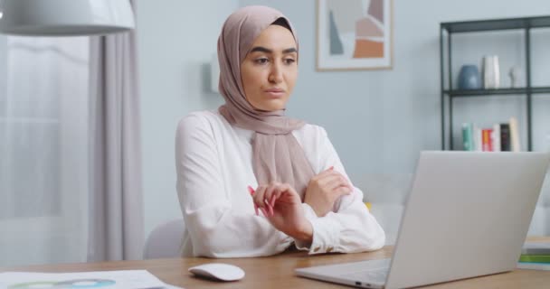 Joven mujer musulmana hermosa terminando proyecto importante, trabajando en la computadora. Chica segura y satisfecha mirando desde la pantalla del ordenador portátil a la cámara. Negocios exitosos, trabajo remoto, concepto de oficina en casa . — Vídeo de stock